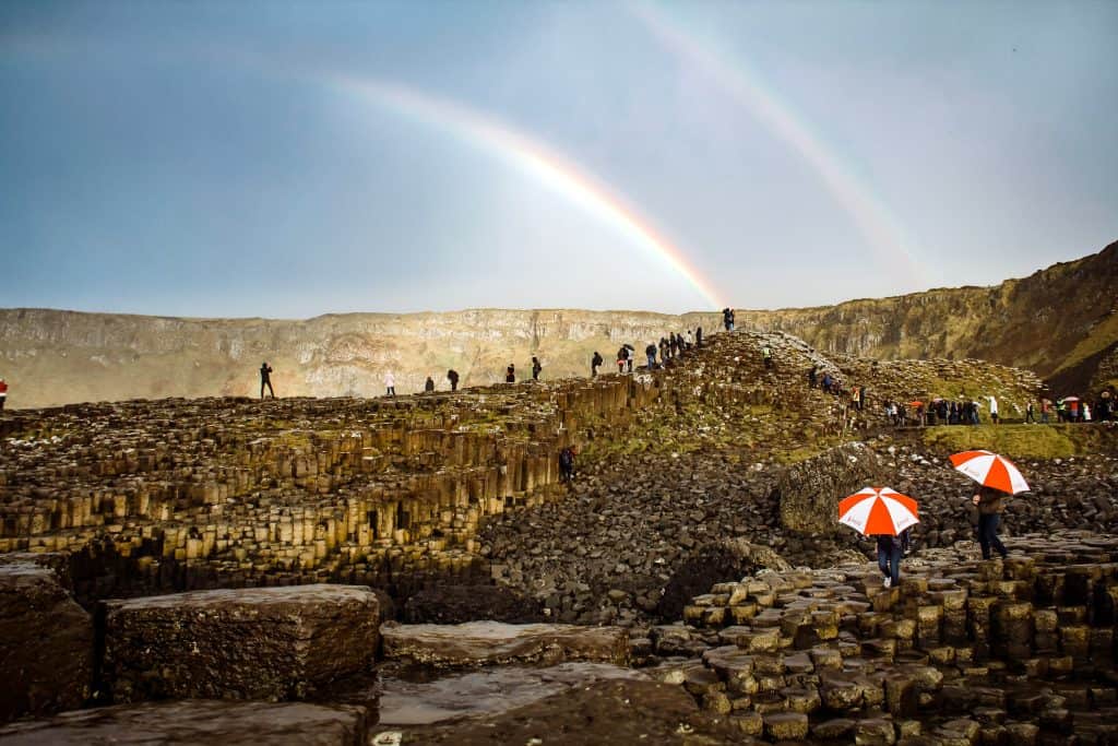 two person holding umbrella in front of hill